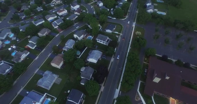 Dusk aerial, suburban neighborhood, overhead flyover, shot at dusk.