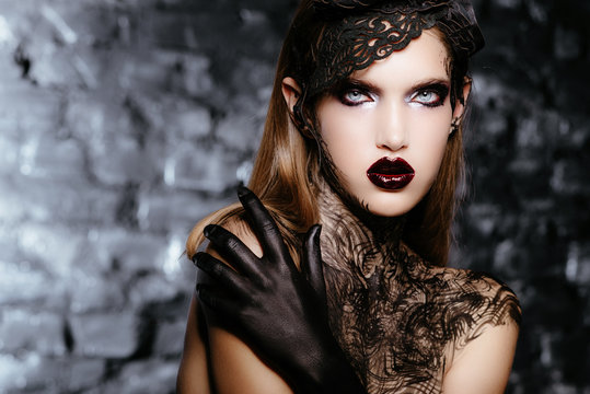 Beautiful girl with long dark hair and black hands in the form of a dark queen of Halloween. Creative make-up. Advertising Space