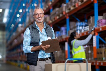 Warehouse manager smiling and holding clipboard