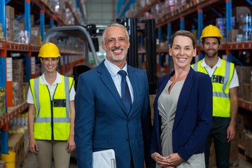 Portrait of warehouse manager standing with client