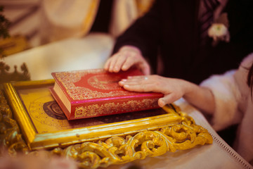 Bride and groom hold their palms over a red Bible