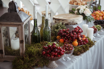 Wedding decor table with fruits, candles and bottles - 124113706