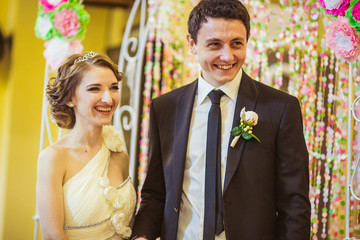 Charming laughing newlyweds stand before pink altar