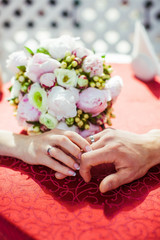Obraz na płótnie Canvas Bride and groom lies their hands on the table before wedding bou