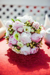 Wedding bouquet made of pink and white peonies lies on the red t