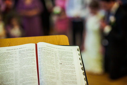 Look over the Holy Bible at wedding couple standing on knees