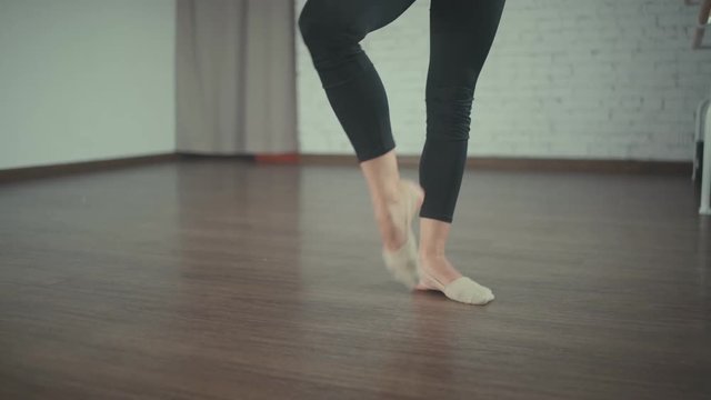 Graceful girl practicing ballet in the Studio. Close-up of legs of a dancer. Trained legs of a ballerina. The fifth dance position. Dancer makes a pli . Exercises about the dance choreography bar