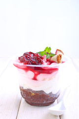 cheesecake with a cherry in a glass decorated with mint on a white background