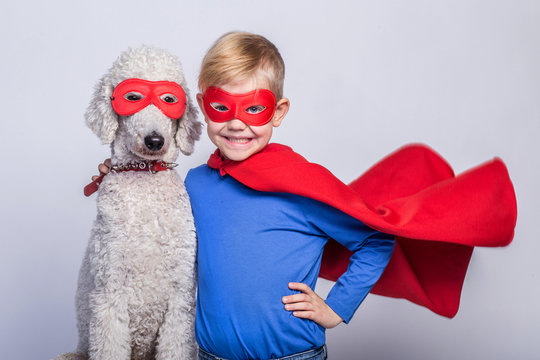 Handsome little superman with dog. Superhero. Halloween. Studio portrait over white background