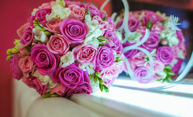 Gorgeous wedding bouquet lies behind the mirror
