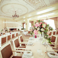 Long dinner tables stand in the restaurant hall with luxurious d