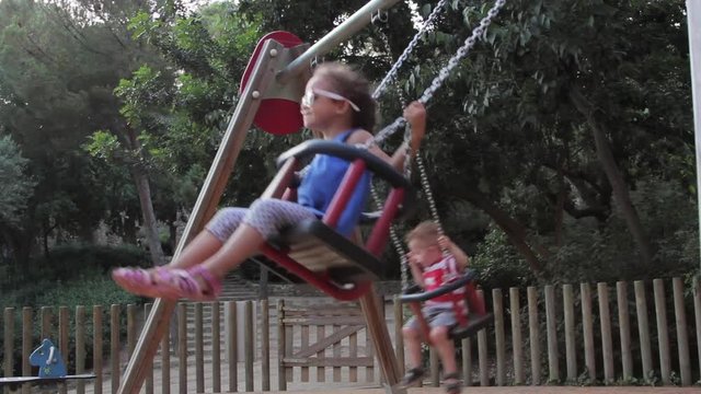 Young children on swings in Park Guell located in Barcelona, Spain.