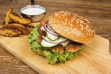 Homemade hamburger with fresh vegetables, potato and sauce on wooden table. 