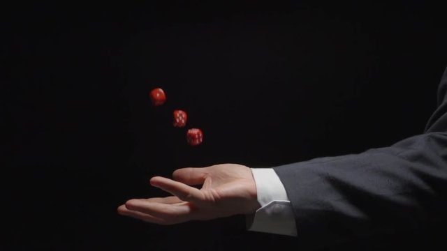 SLOW MOTION: Businessman hand throws up several red playing cubes (side view)