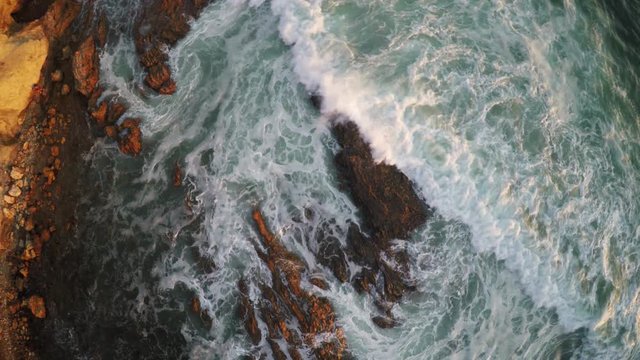 Aerial bird's eye view, waves crash in Corona Del Mar, California.