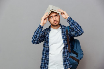 Young bearded male student with open book on his head