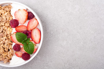 Granola for breakfast with berries and yogurt on grey stone background. Healthy eating oatmeal. Concept healthy lifestyle and diet. Top view. Copy space