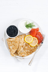 Traditional crepes with fish, sour cream and caviar, top view