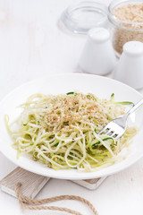 vegetarian pasta with zucchini and nuts on white table, vertical