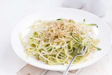 vegetarian pasta with zucchini and nuts on white table