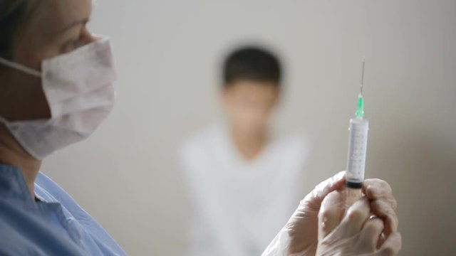 Cute little boy afraid of injection. nurse prepares a syringe