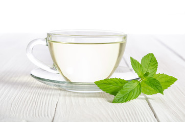 Glass cup of tea with mint on the white wooden table
