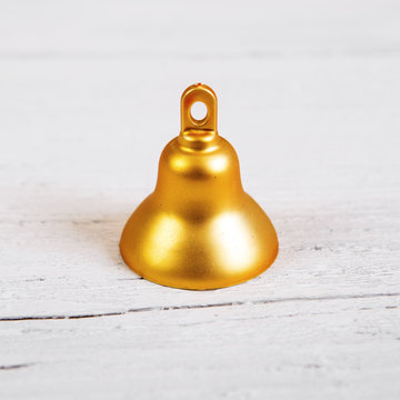 Brilliant gold bell like christmas decoration. Isolated on white wooden background.