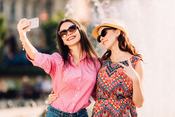 two pretty fresh hipster young brunette and blonde best friends girls,make selfie and having fun.