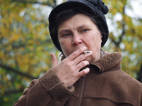 Woman at the age of smoking a cigarette. Social problems - addictions, poverty