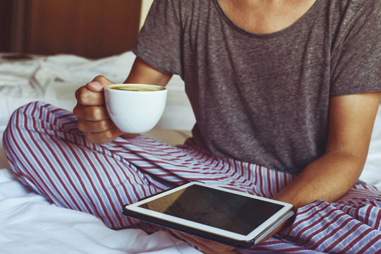 Young Man In Pajamas Using A Tablet Computer