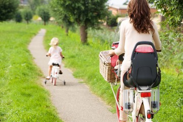 Woman and little girl riding bikes in park