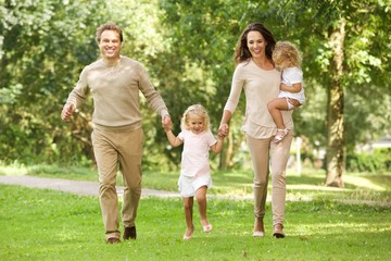 Fototapeta premium Happy young family of four walking in the park