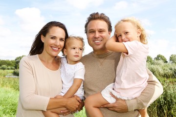 Happy family with two daughters standing outdoors