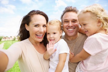 Happy family with two daughters taking selfie outdoors