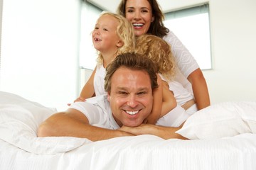 Happy young family enjoying in bed