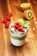 Colorful fruit salad with cream and chocolate in a jar on rustic wooden background