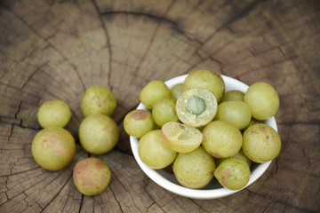 Indian gooseberry in bowl.Wood background with cracks.