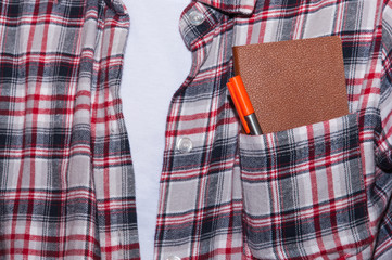 Notebook with pen in pocket of shirt.