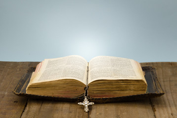 Old leather covered Holy Bible on rough wood table with crystal