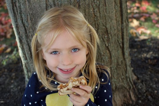 Adorable Young School Age Girl Eating A Peanut Butter Sandwich