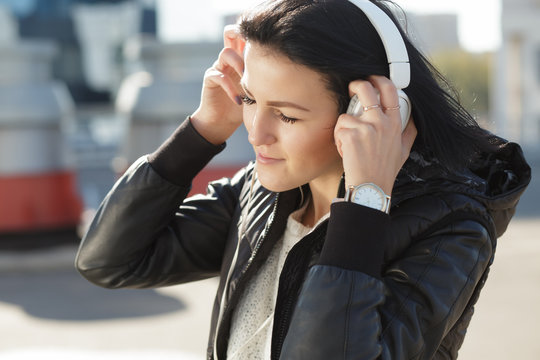 Woman with white earphones listen music in city