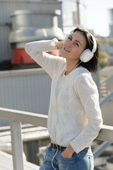 Woman in white earphones listen music at city background