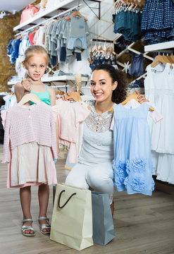 mother with happy daughter buying kids clothes