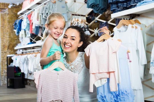young smiling mother with smiling daughter in shop