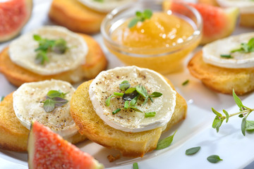 Gebackene Crostini-Partyhäppchen mit Ziegenkäse, frischen Kräutern und Feigenhonig serviert - Baked spicy crostini appetizers with goat cheese and fresh herbs served with fig honey