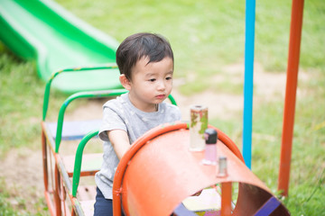 Young Asian boy play a iron train swinging at the playground und