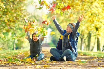 freudig lachende Kinder werfen bunte Blätter im Herbst