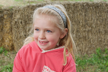 adorable school age girl sitting by haystack