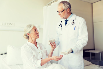 doctor giving medicine to senior woman at hospital