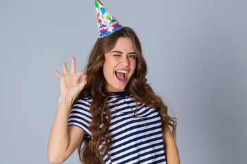 Woman in celebration cap showing okay